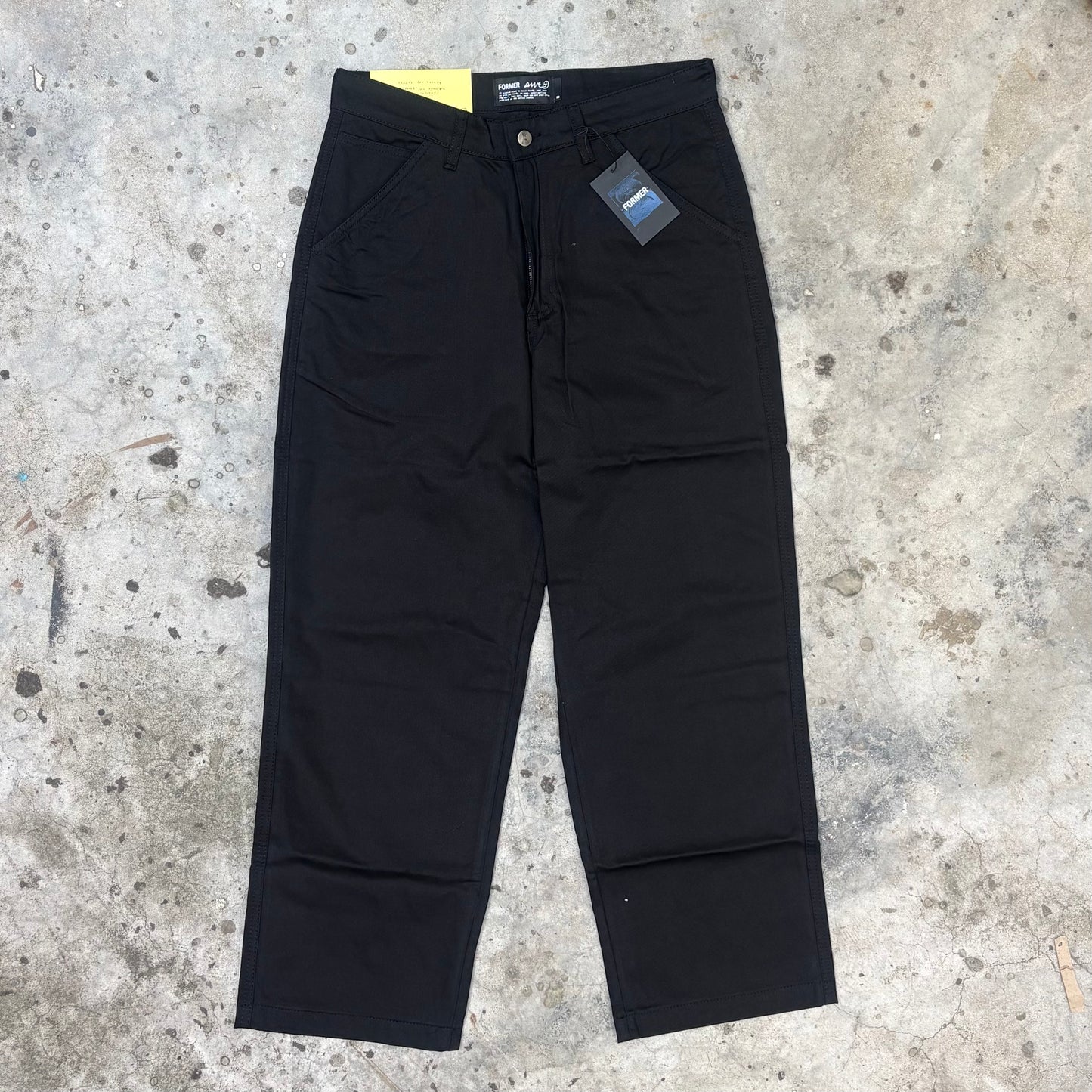 Black pants with a tag on a concrete surface