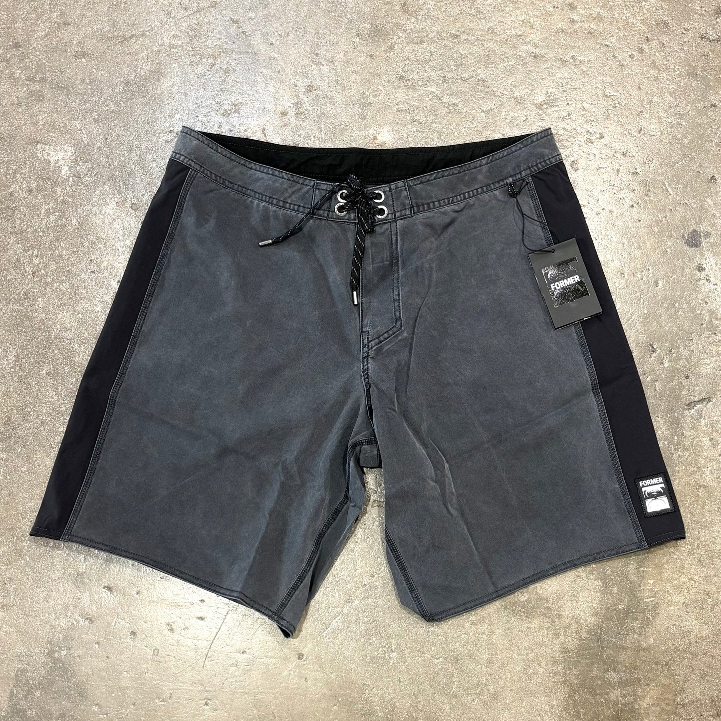 Black shorts with brand tags on a concrete surface