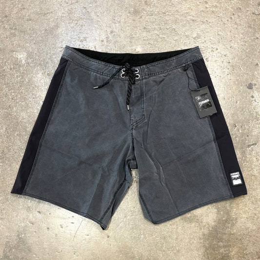 Black shorts with brand tags on a concrete surface