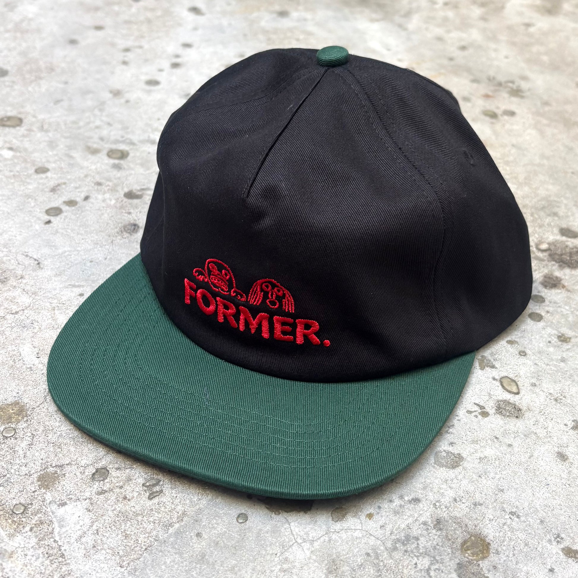 Black and green cap with 'FORMER' logo on a textured surface