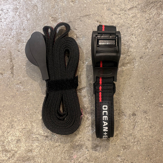 Black webbing strap with a ratcheting mechanism on a gray surface