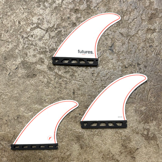 A set of Futures Jordy Signature surfboard fins in a white colour way with red details on a textured surface