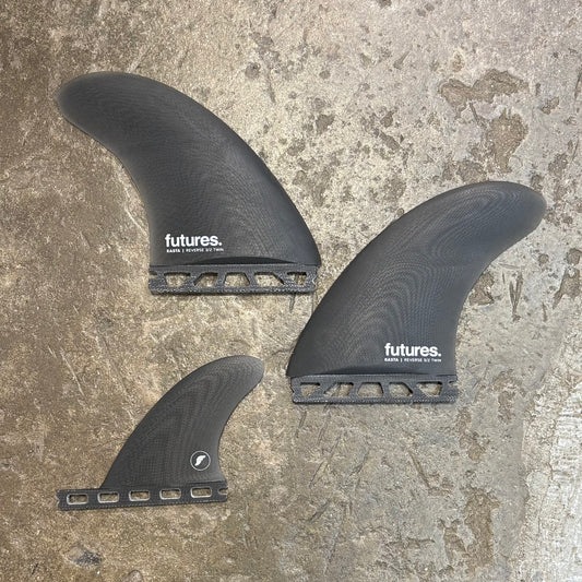 Three black surfboard fins with 'futures' branding on a textured surface.