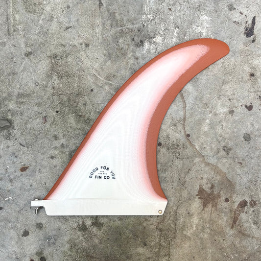 Fiberglass surfboard fin with red and white design on a concrete surface
