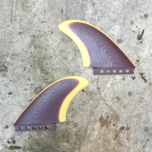 Two purple and yellow surfboard fins on a concrete surface
