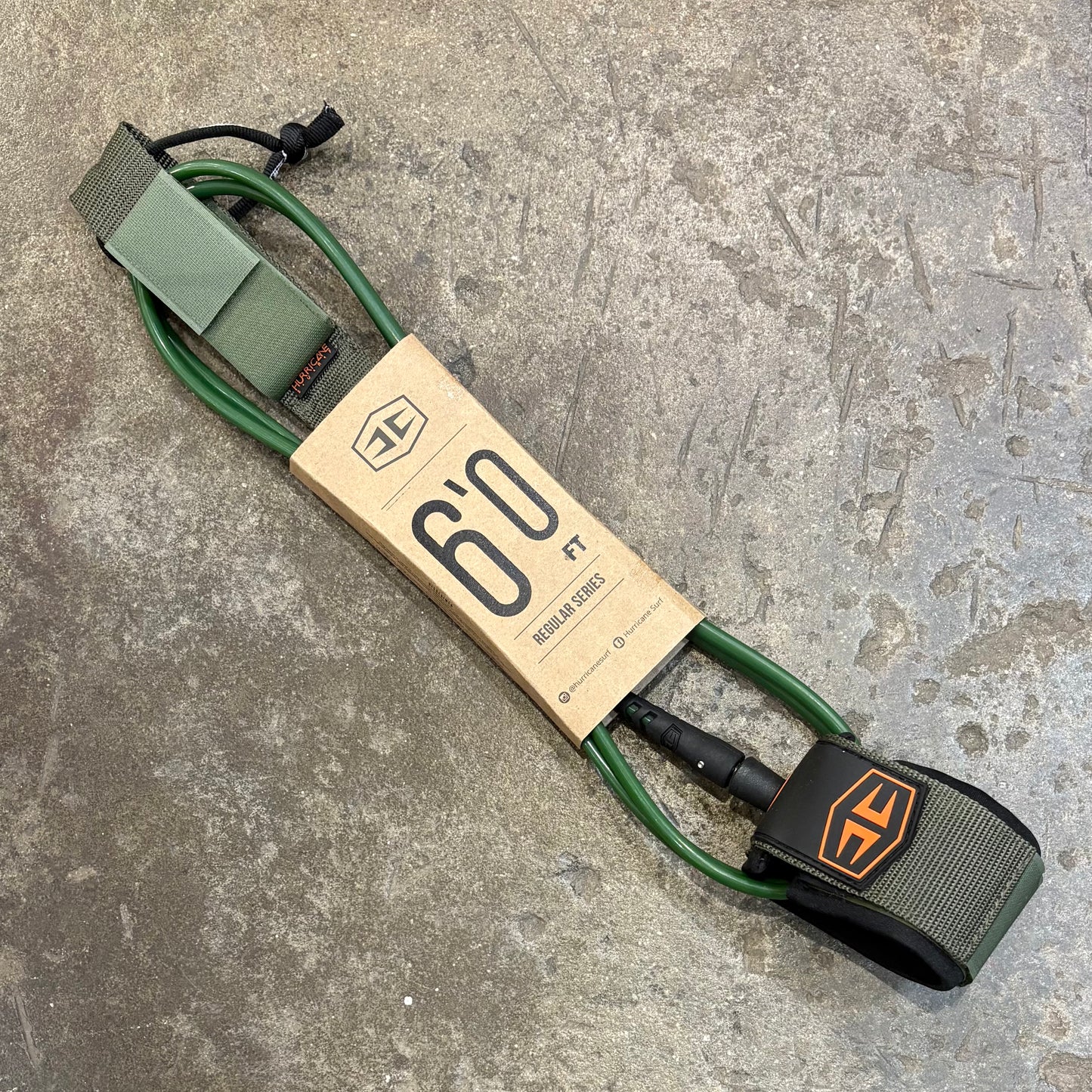 Green and black surfboard leash with Hurricane logo on a textured surface