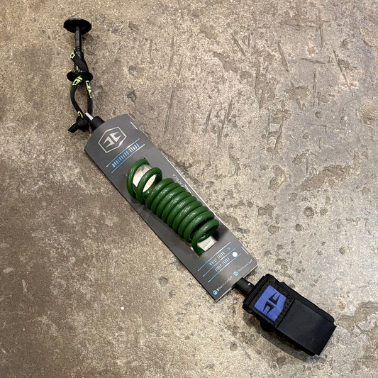 Green coiled bodyboarding leash with a black strap on a textured surface