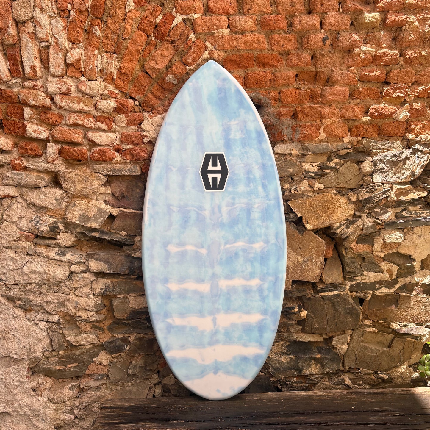 Blue skimboard with a logo against a stone wall