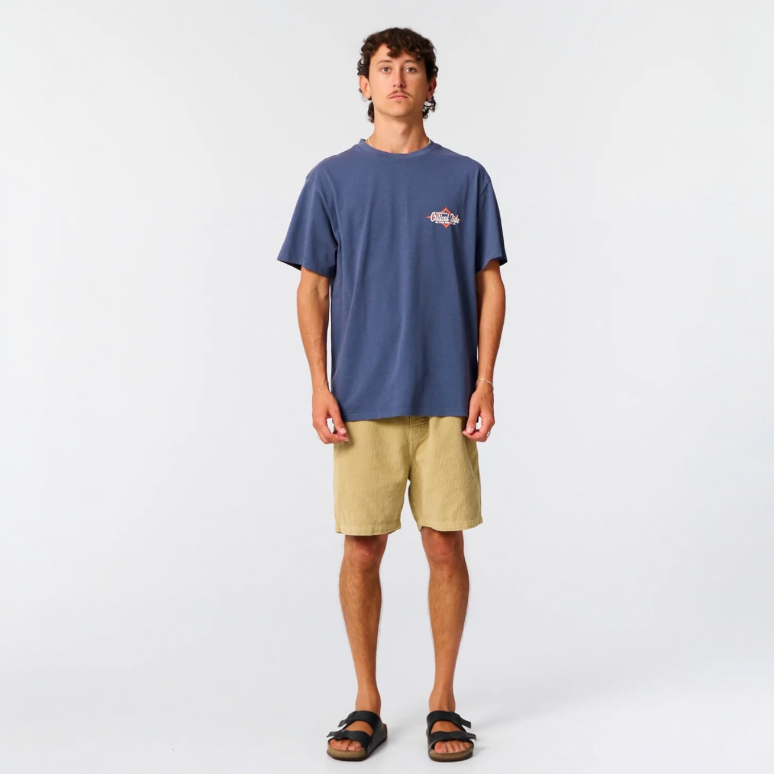Person wearing a blue t-shirt and beige shorts on a white background