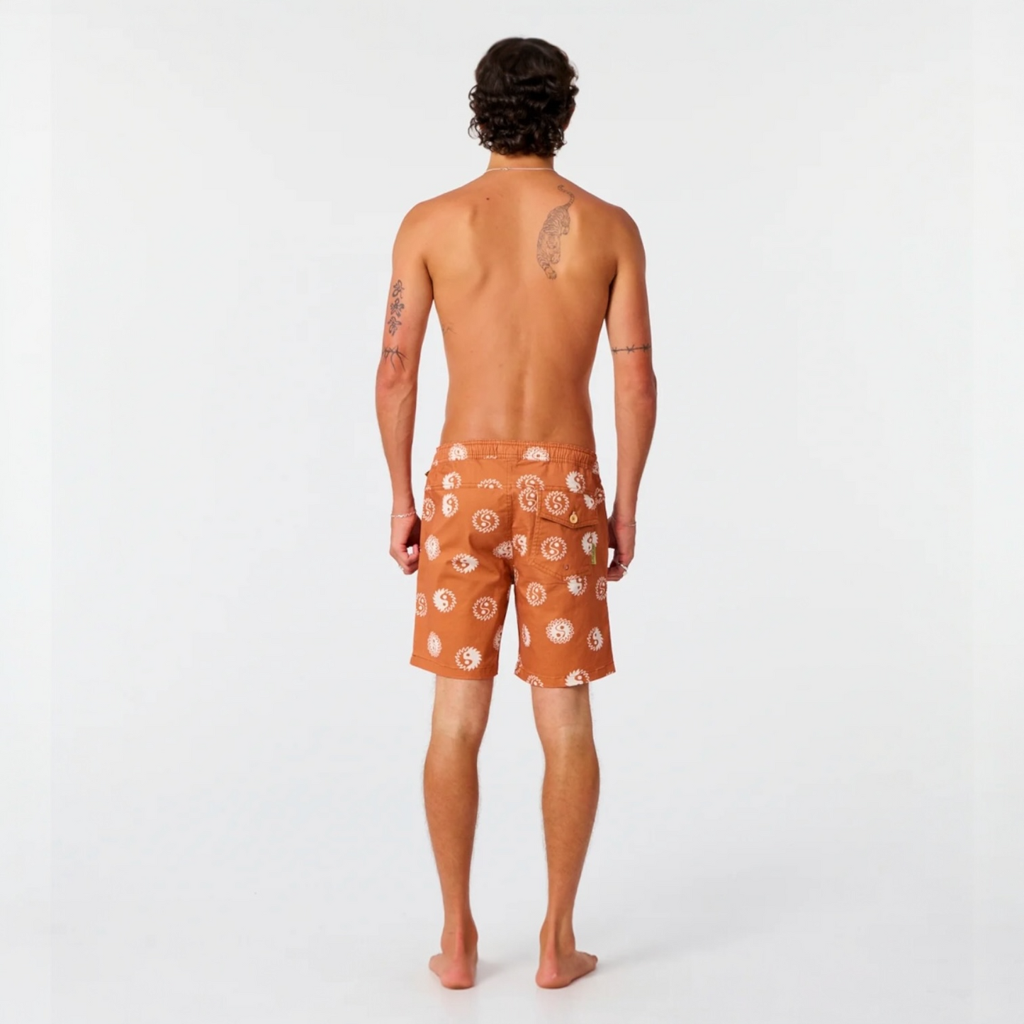 Man wearing orange swim shorts with a pattern on a white background