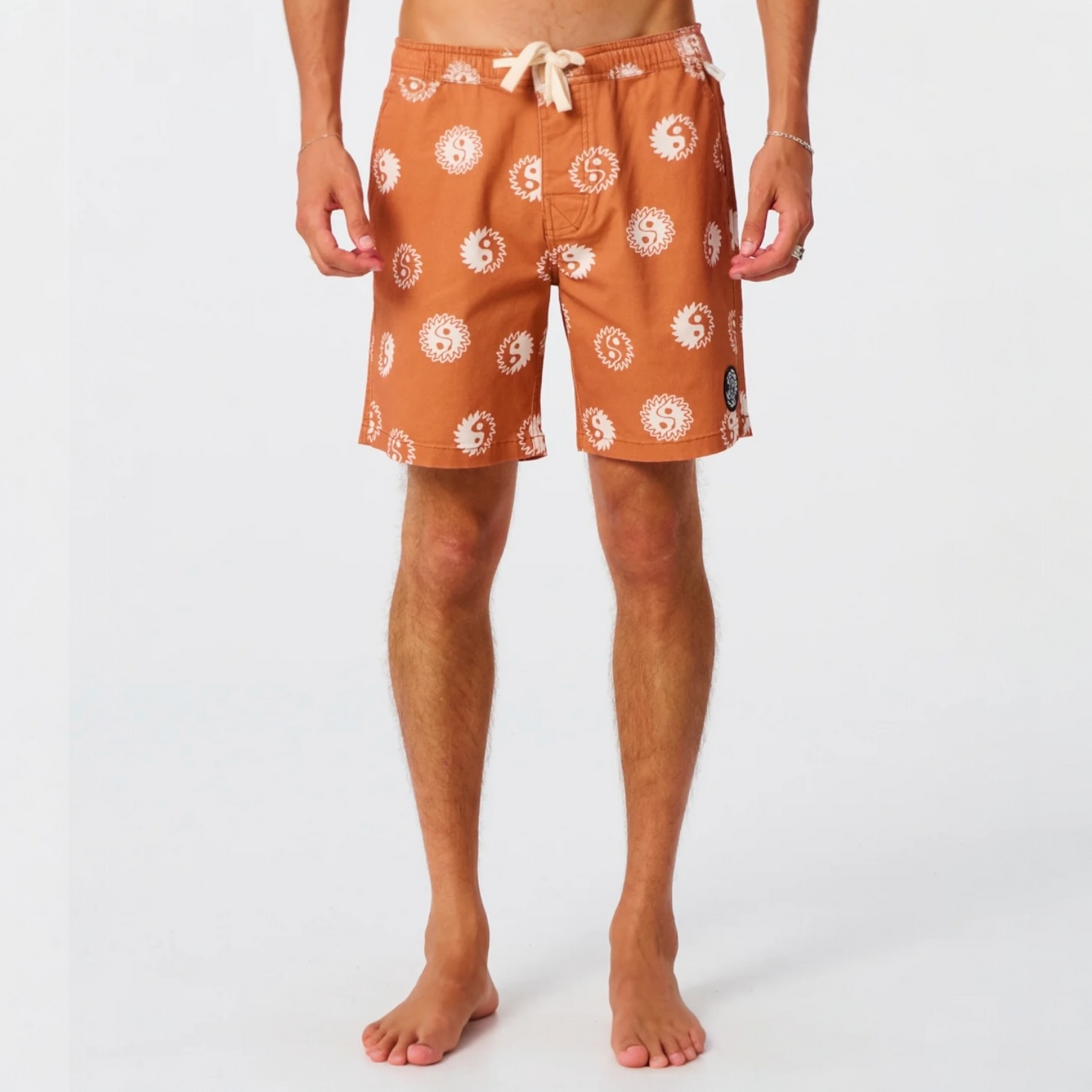 Person wearing orange swim shorts with white patterns on a white background