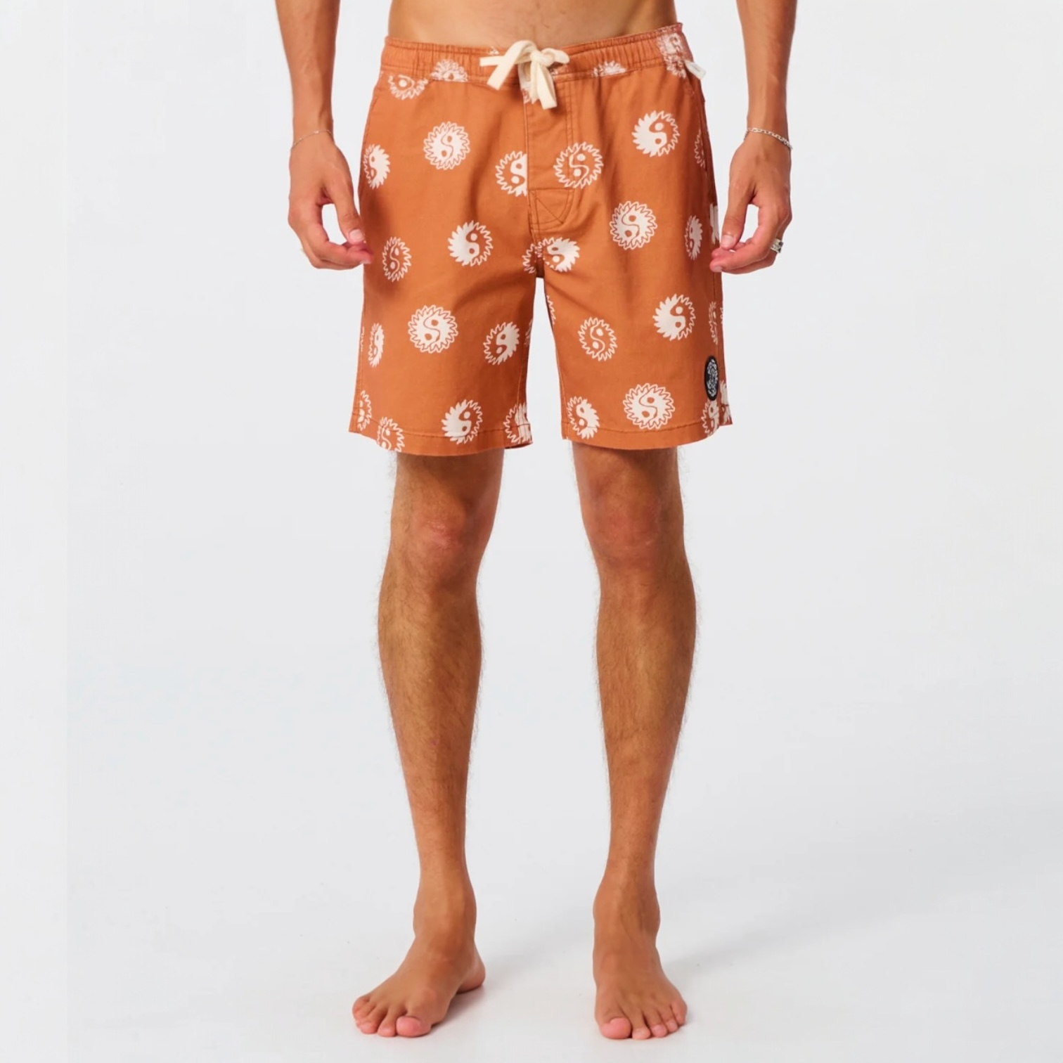 Person wearing orange swim shorts with white patterns on a white background