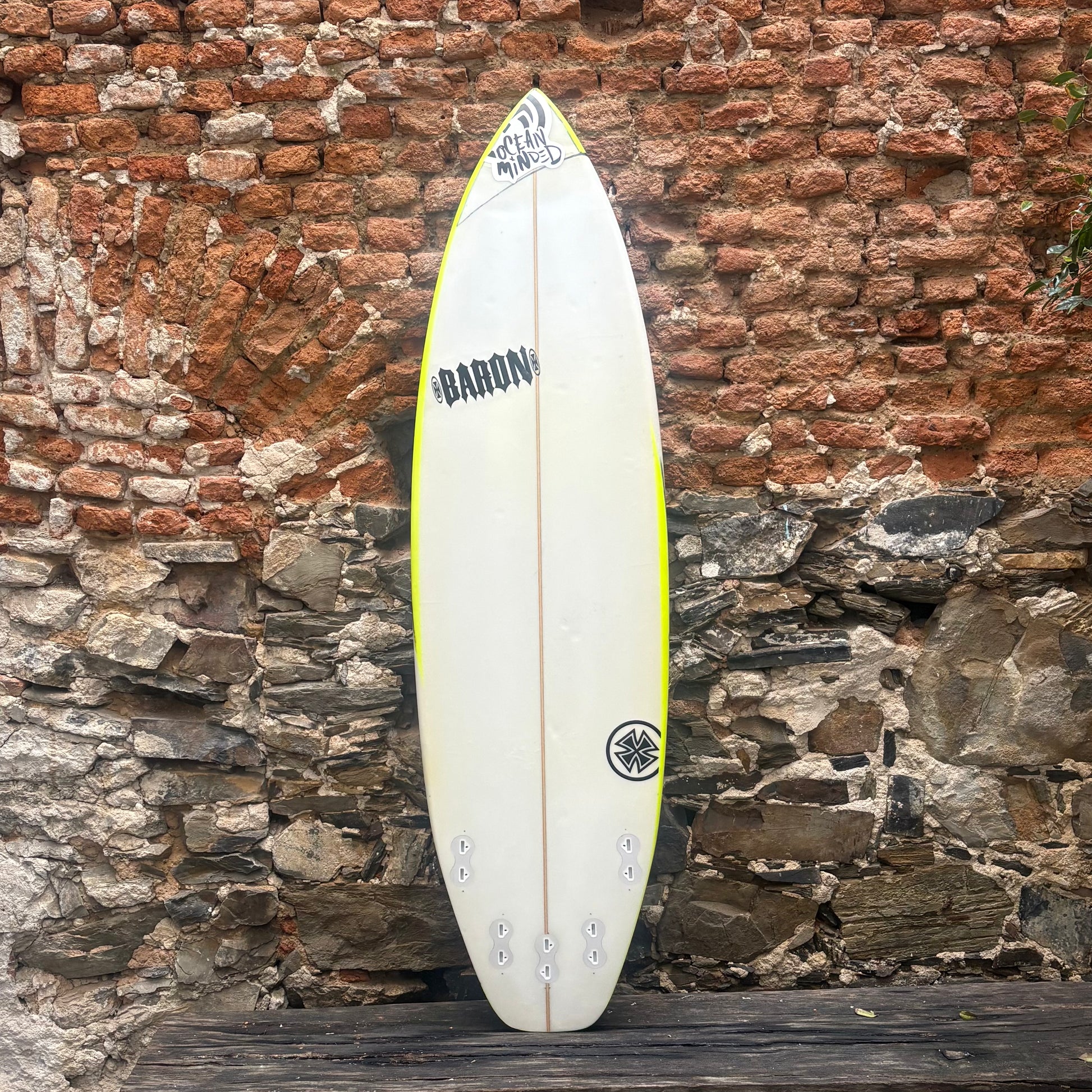 White surfboard with branding against a rustic stone wall