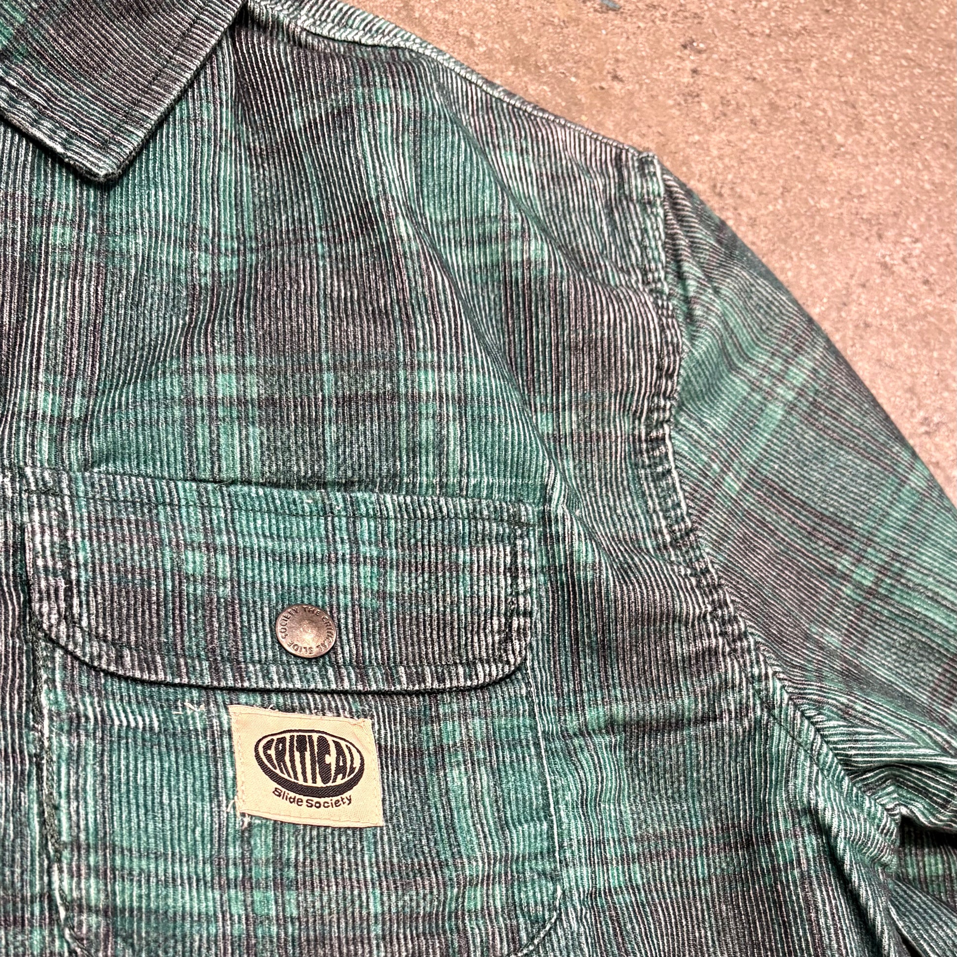 Green corduroy jacket with a brand label on a textured surface