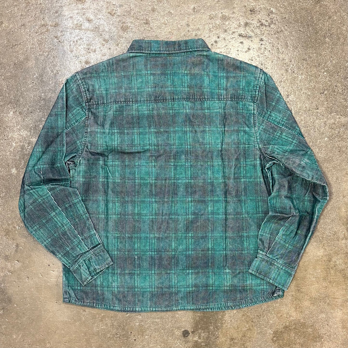 Green plaid shirt on a textured concrete surface