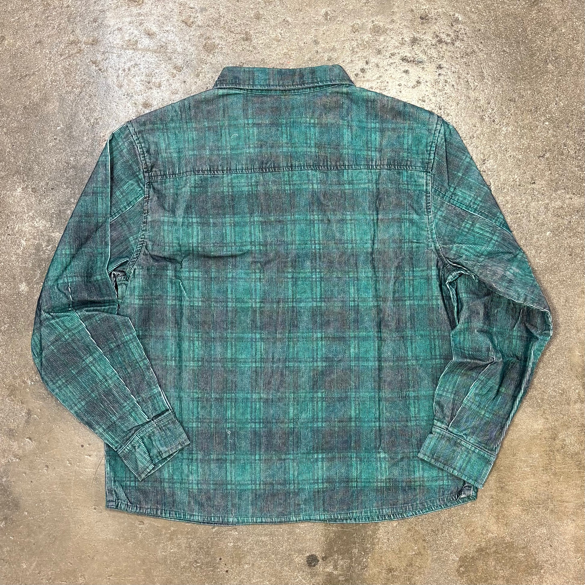 Green plaid shirt on a textured concrete surface