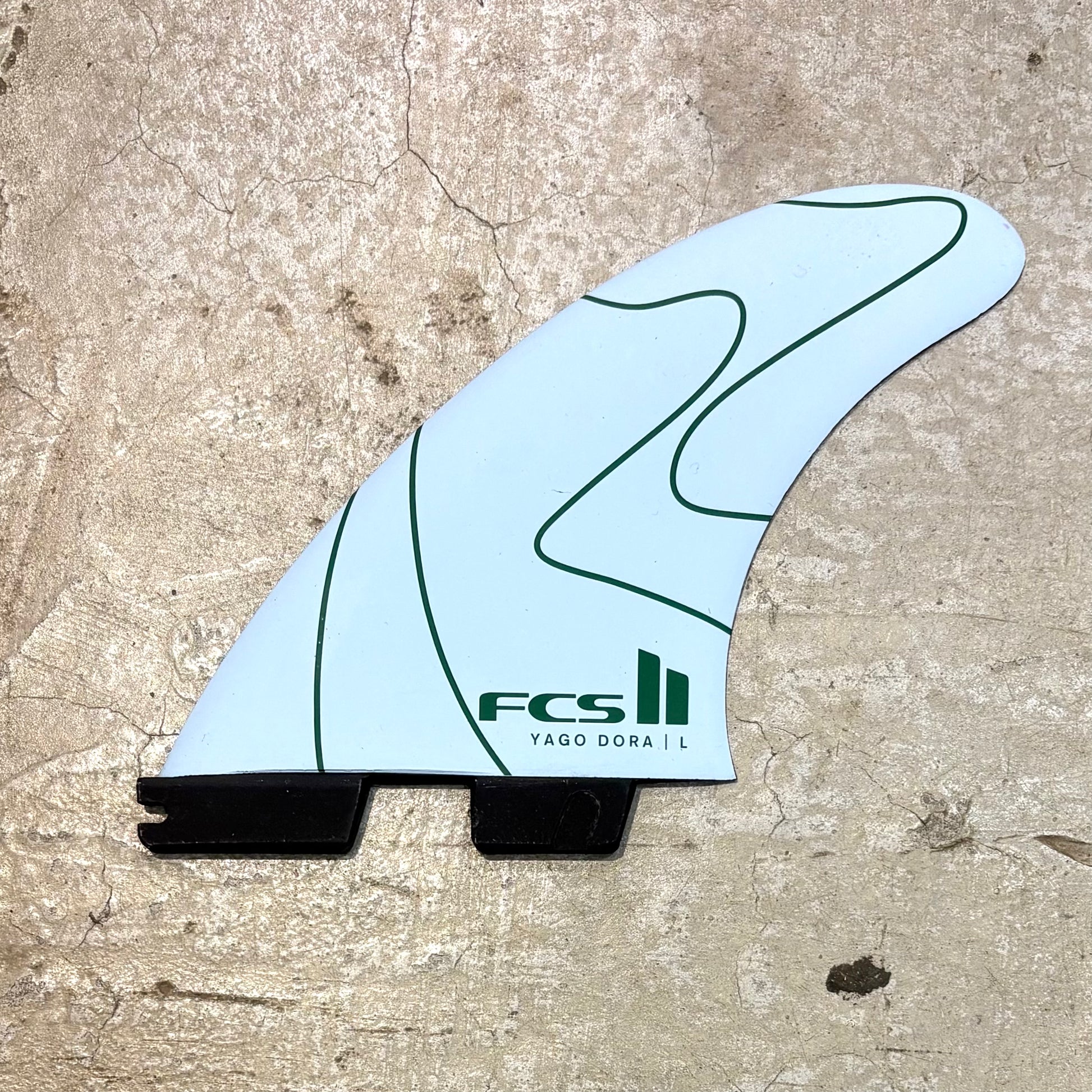 Surfboard fin with FCS logo on a textured surface