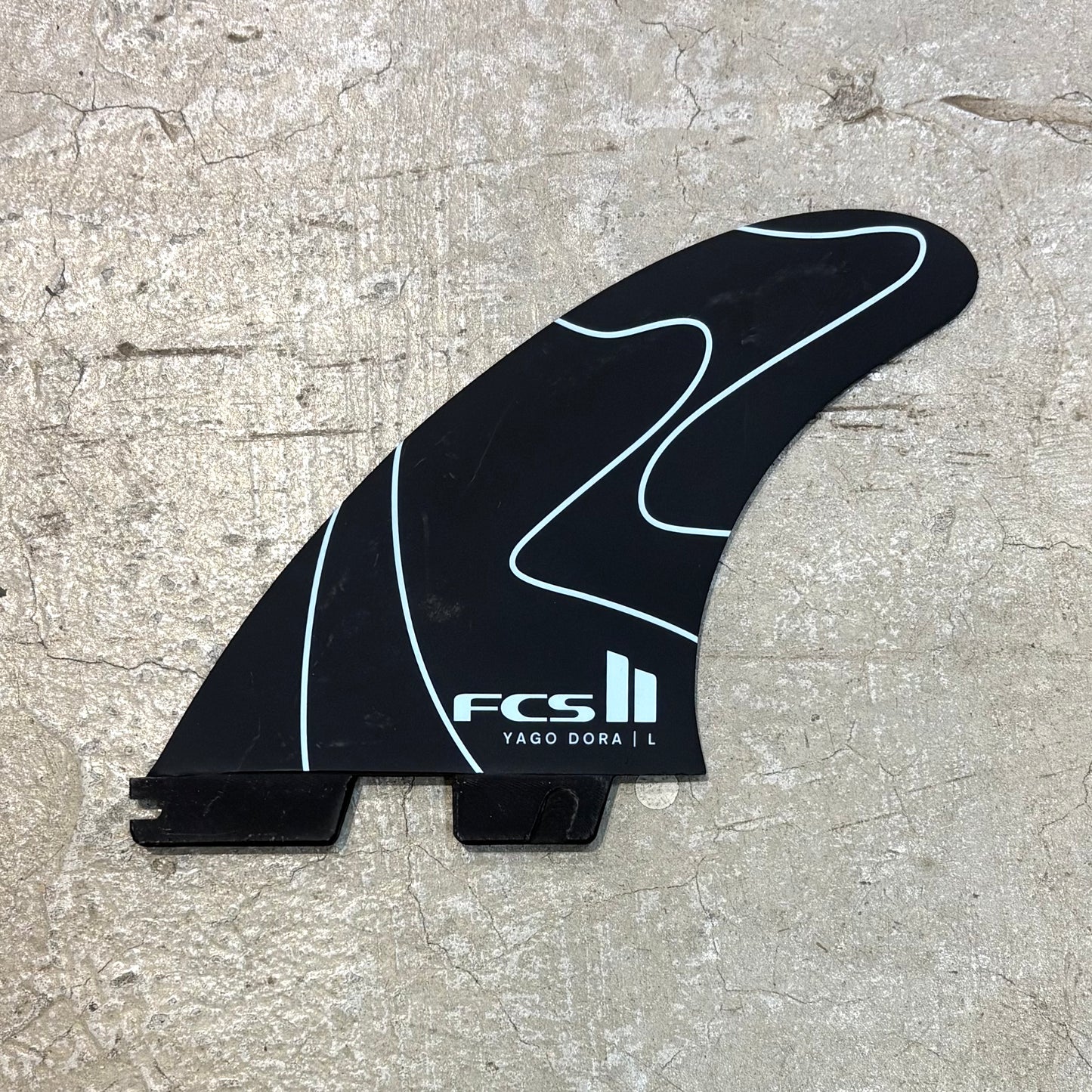 Black surf fin with white branding on a textured surface