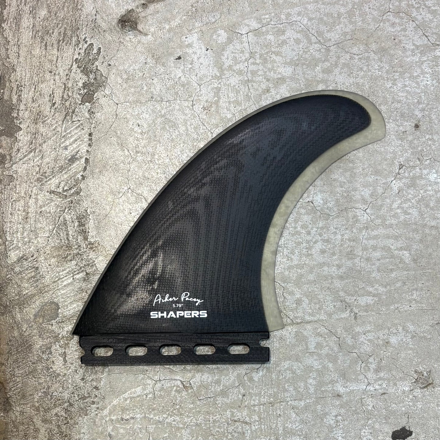 Black surf fin with 'Shapers' branding on a textured surface