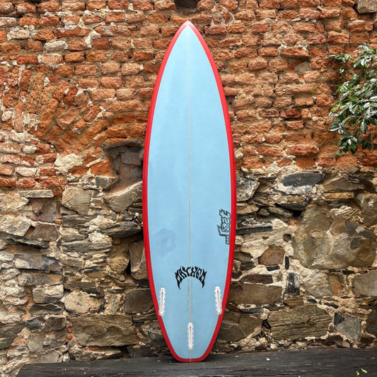 Blue and red surfboard leaning against a brick wall.