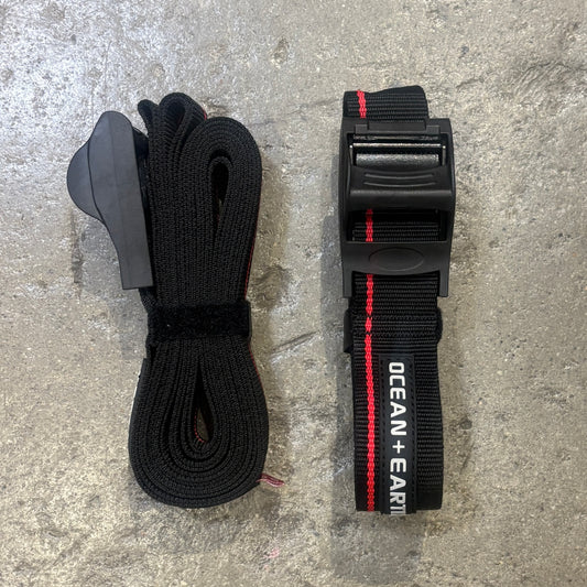 Two black straps on a concrete surface, one with a visible brand name.