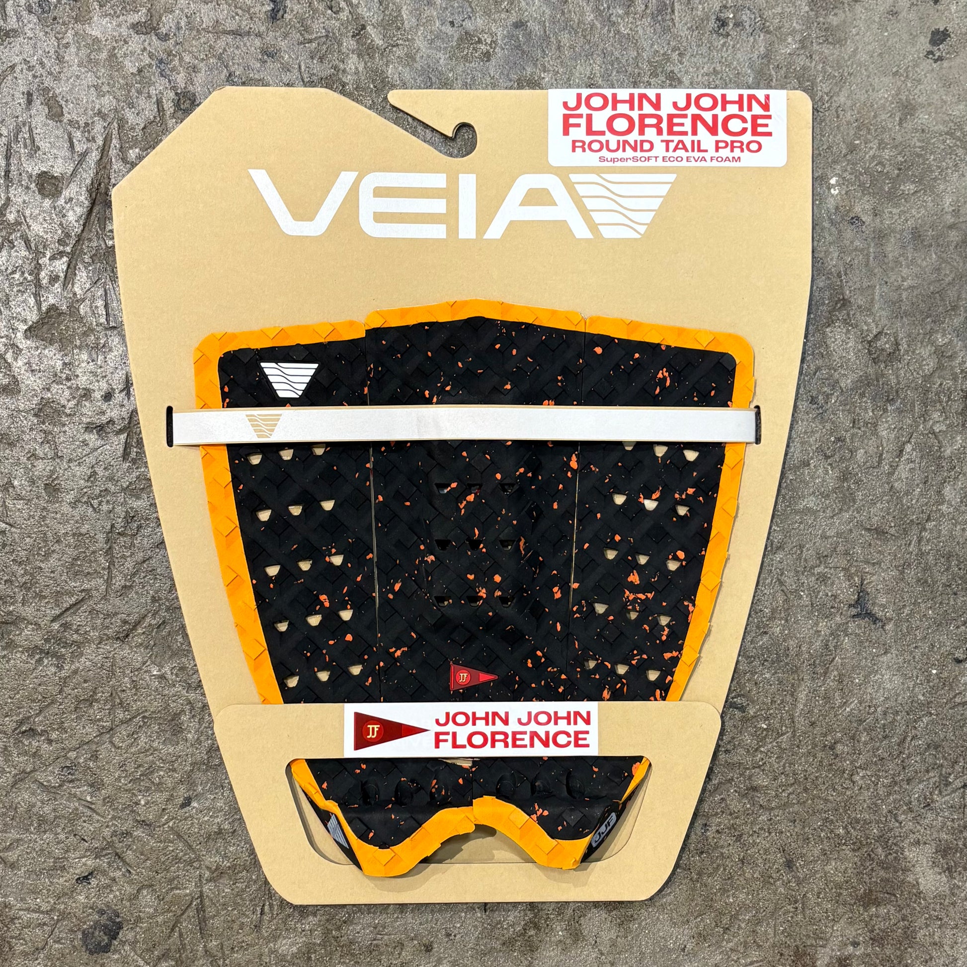 Veia John John Florence round tail pro surfboard tail pad packaging on a textured gray background
