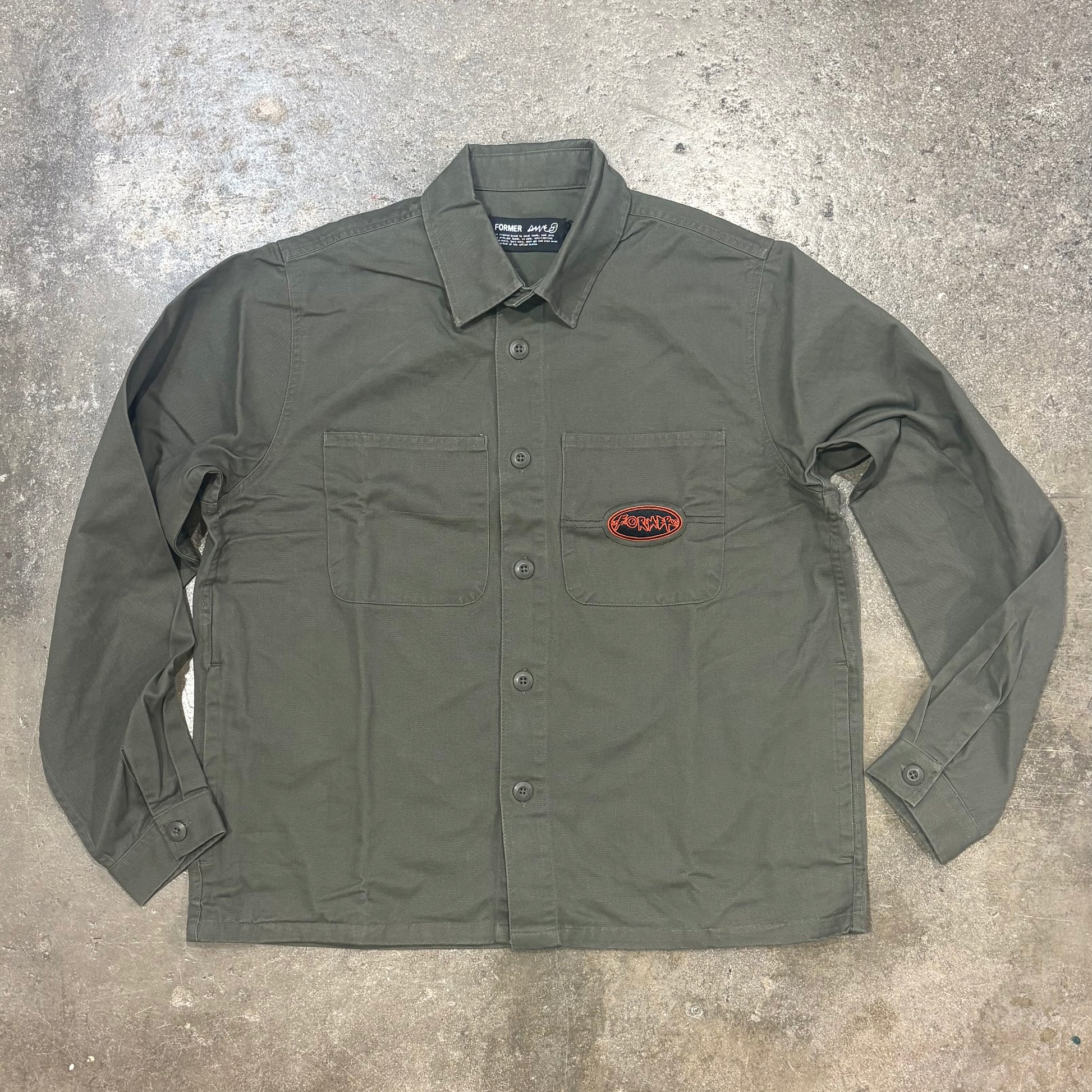 Green shirt with a logo on a gray concrete surface