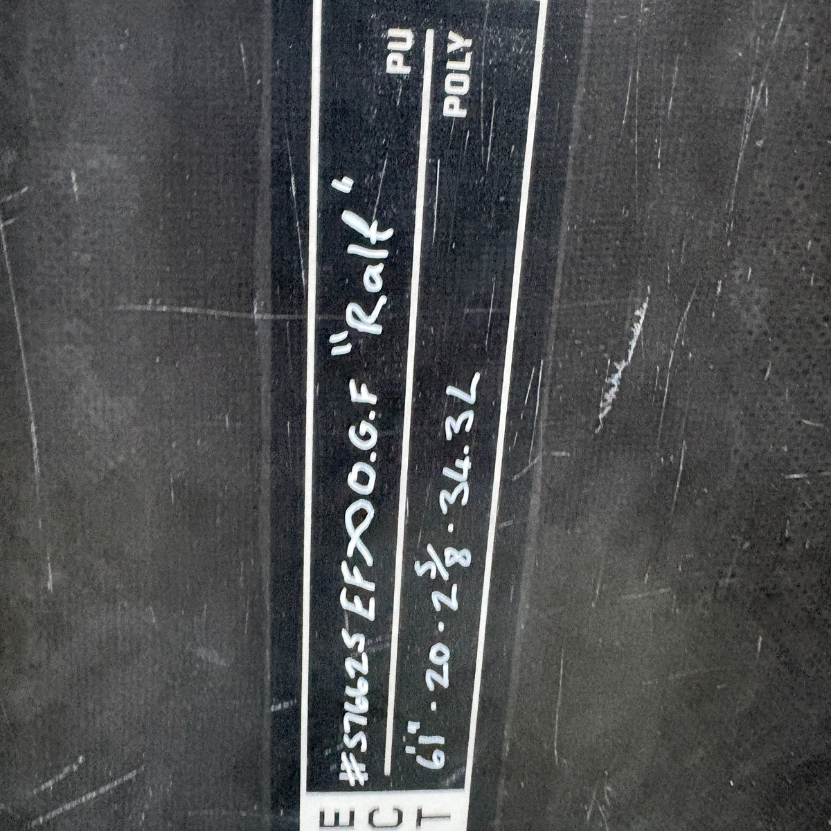 A close-up of a black textured surface with a vertical white label containing handwritten text and the partial brand name ECT.