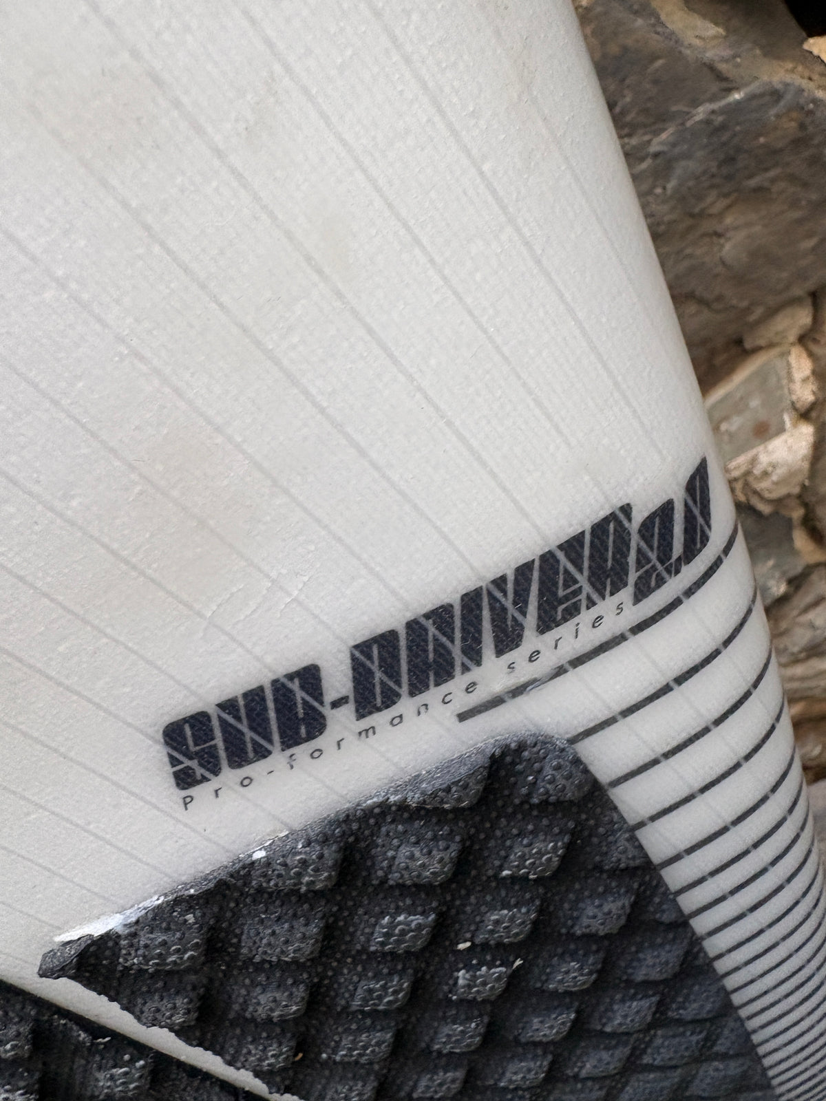 Close-up of a white textured shoe or boot with black printed branding reading 'COLD-DRIVEN' and 'performance series,' plus a black textured grip section at the bottom.