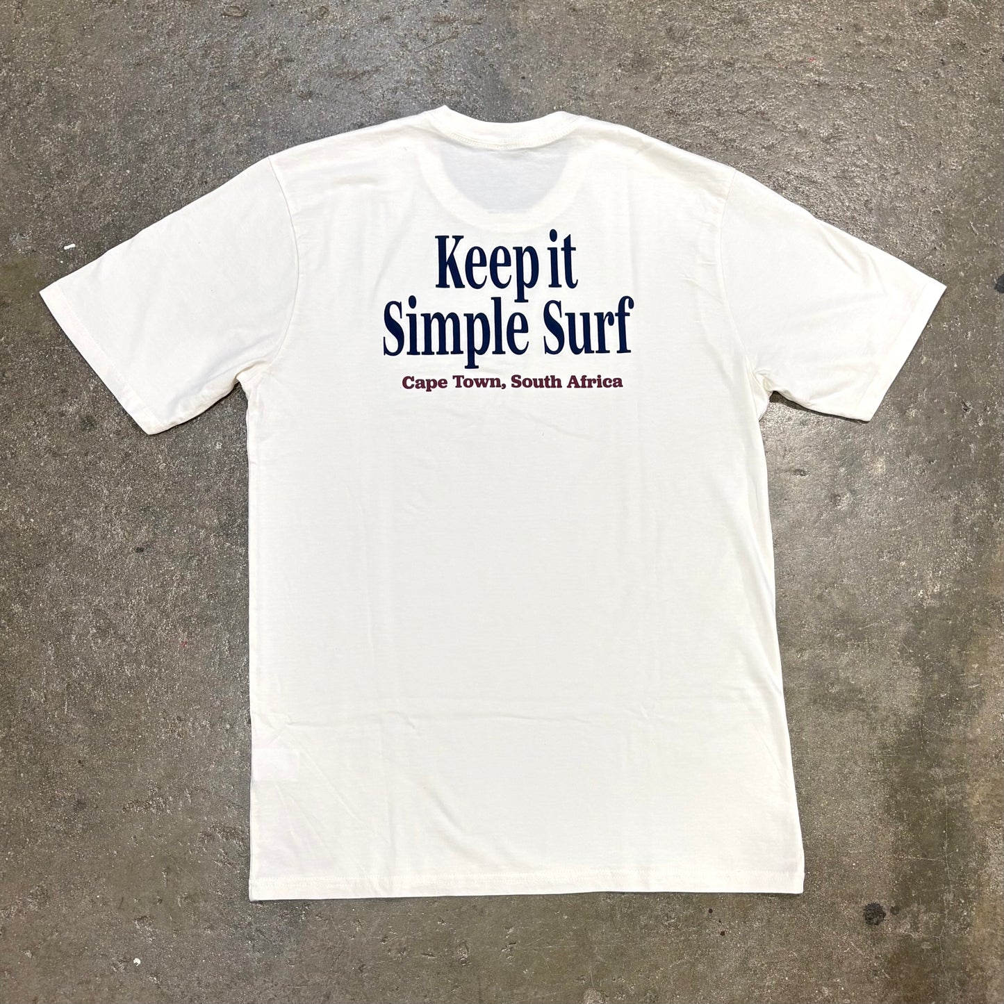 White t-shirt with 'Keep it Simple Surf' text on a textured gray background