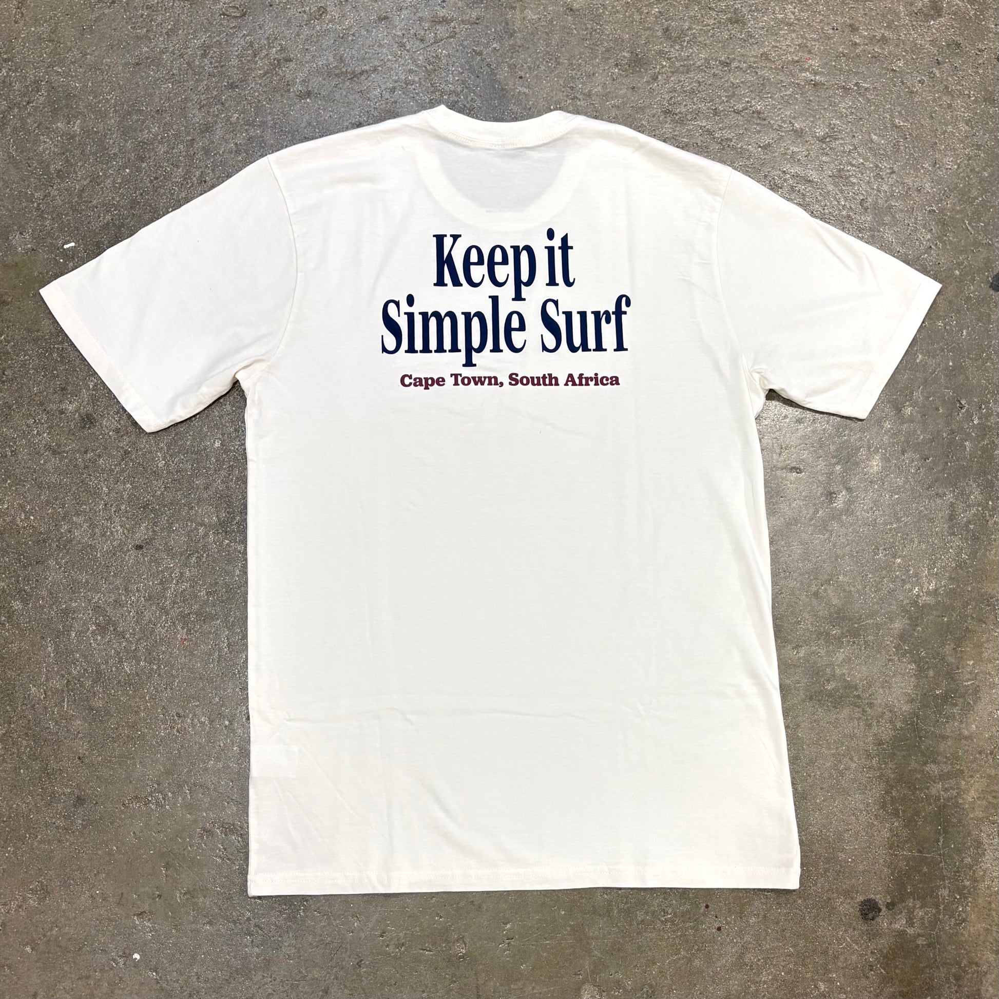 White t-shirt with 'Keep it Simple Surf' text on a textured gray background