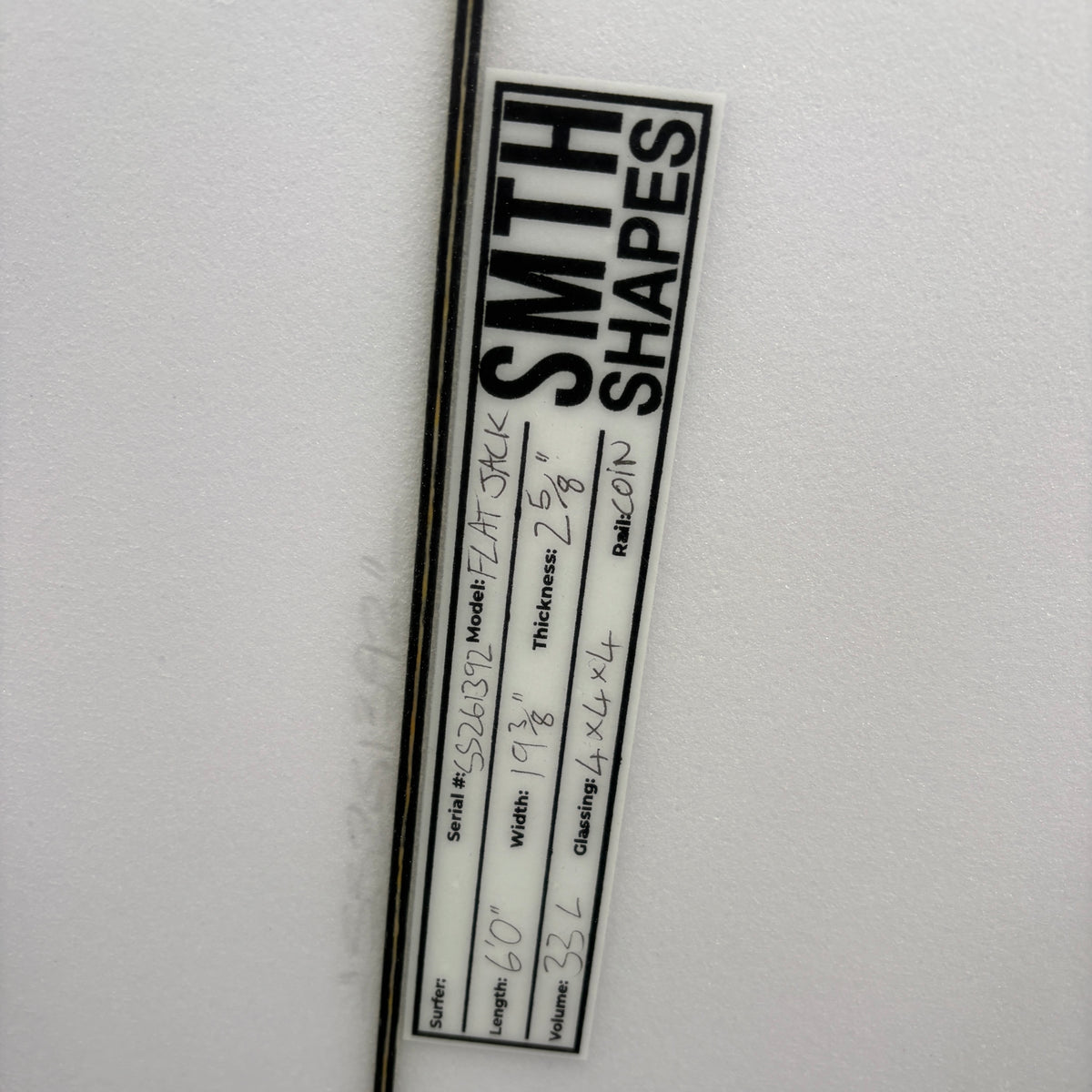A close-up of a white cylindrical product with a black printed label reading 'SMITH SHAPES' and handwritten measurements on the side.