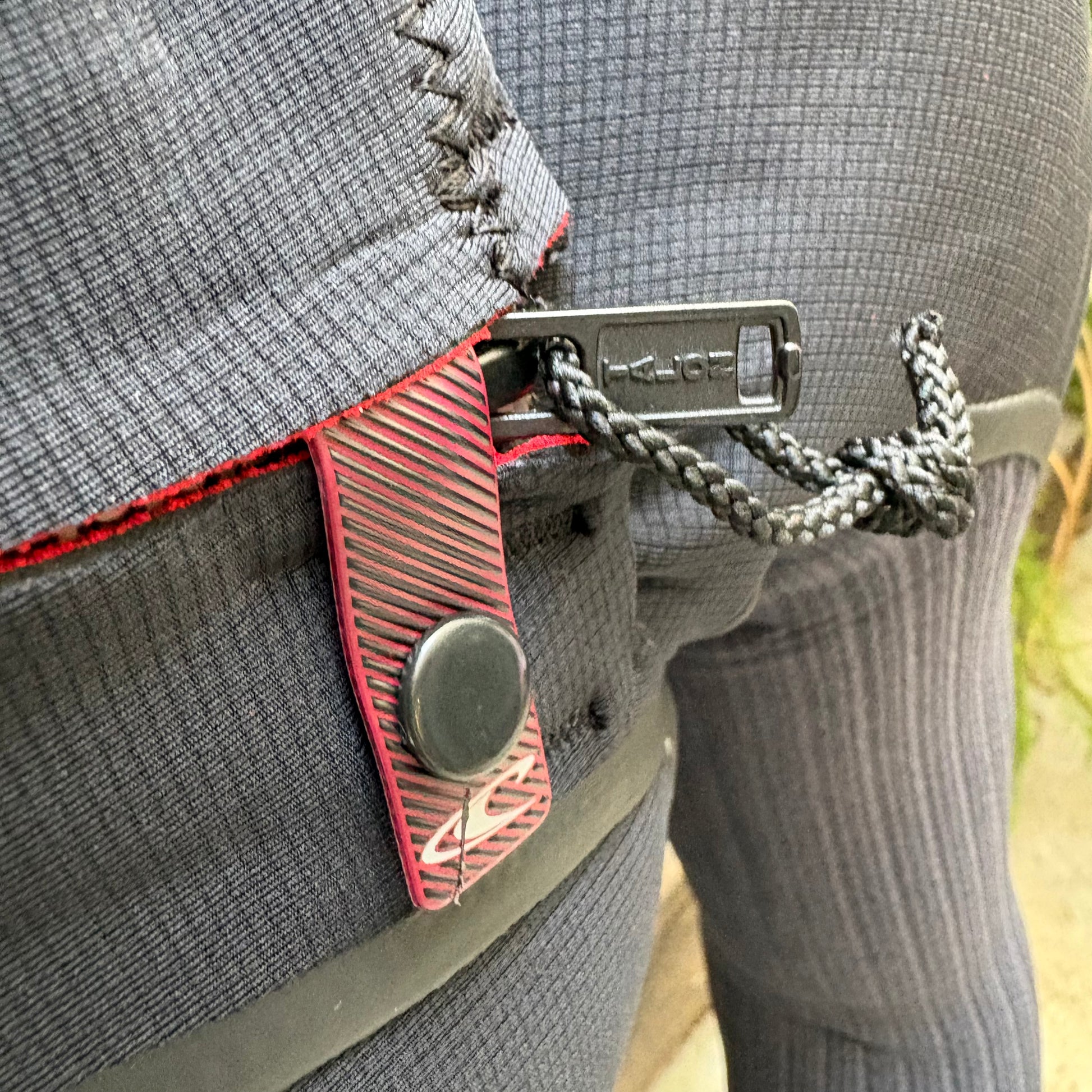 Close-up of a gray backpack with red accents and metal hardware.