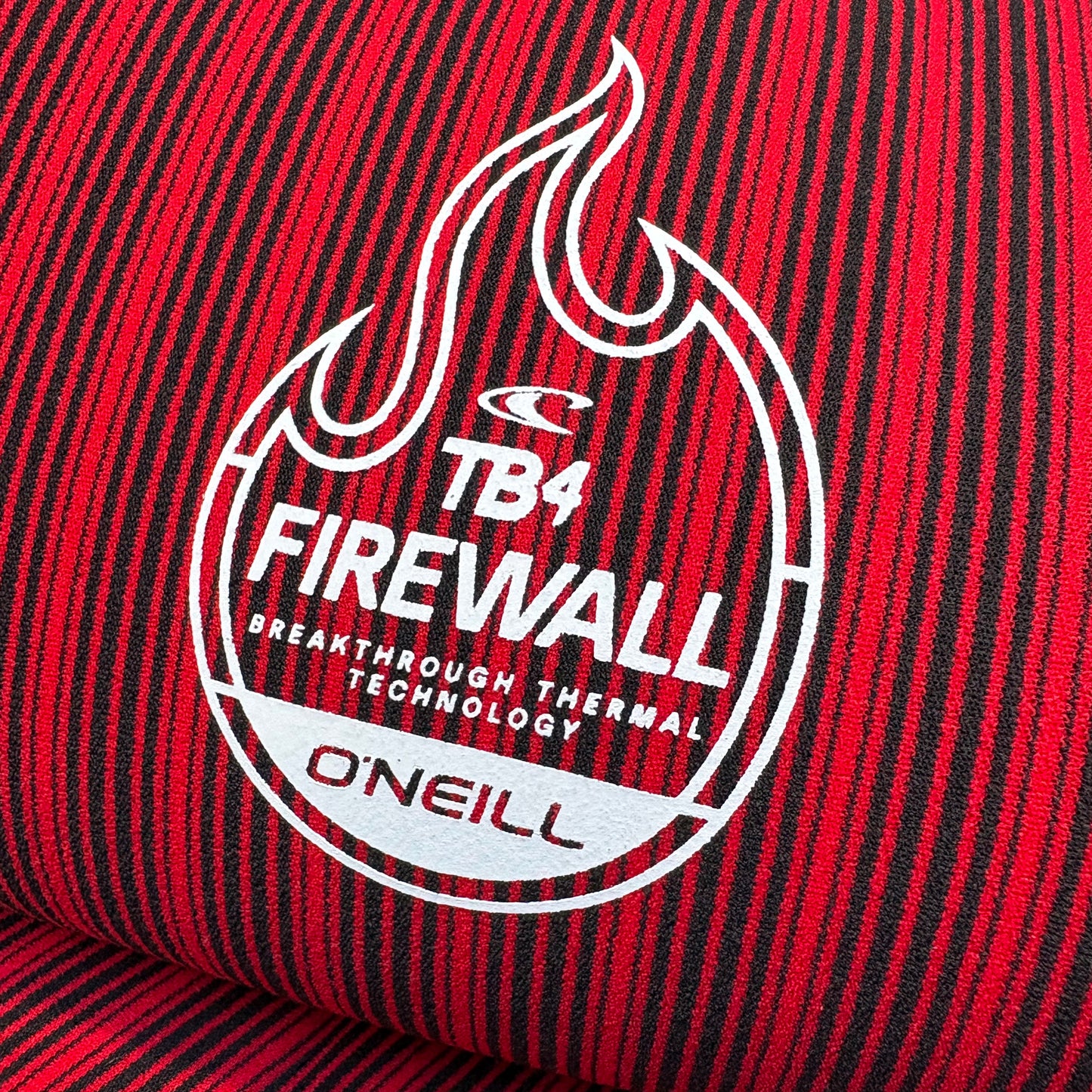 Close-up of a red and black striped fabric with a white logo and text on a red background.