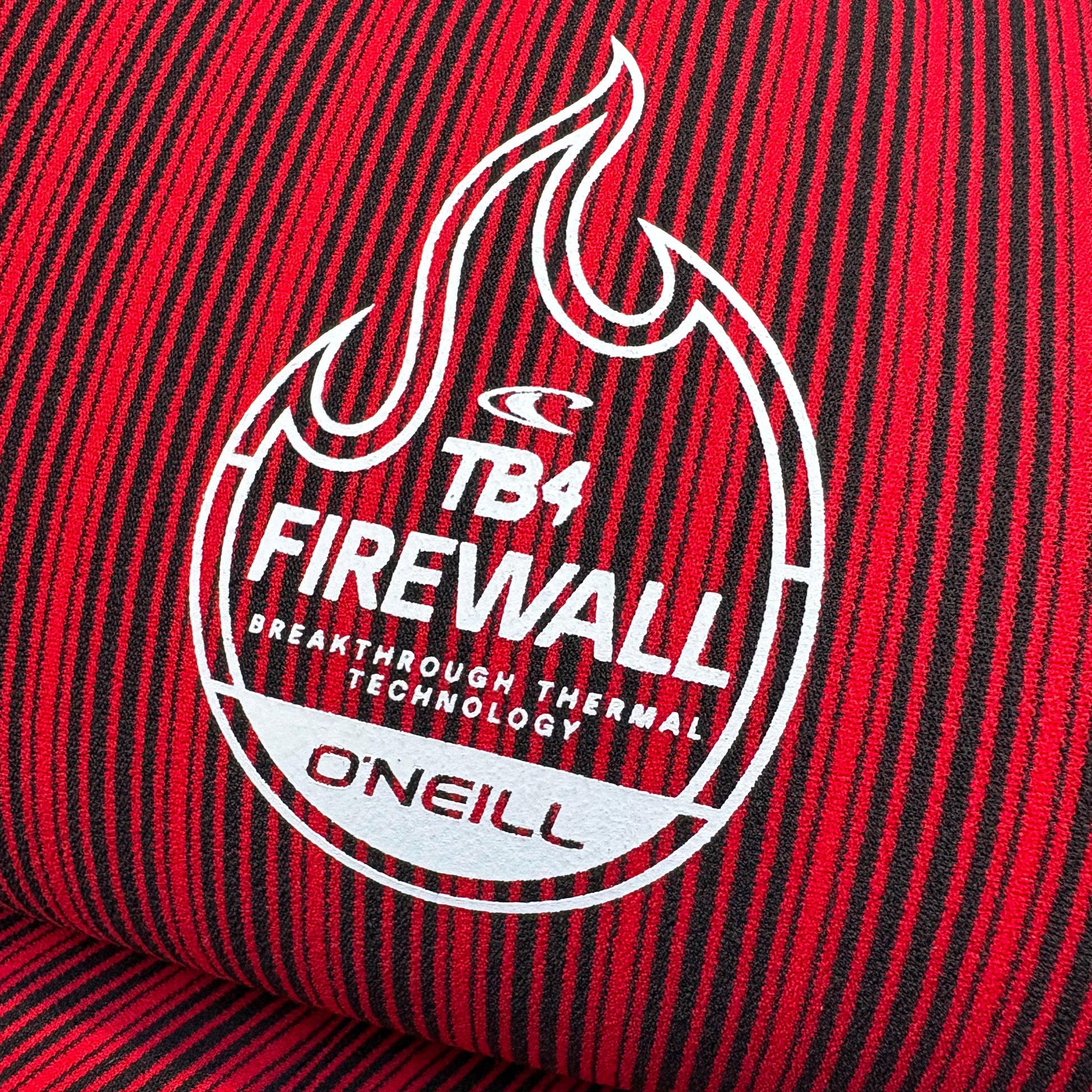 Close-up of a red and black striped fabric with a white logo and text on a red background.