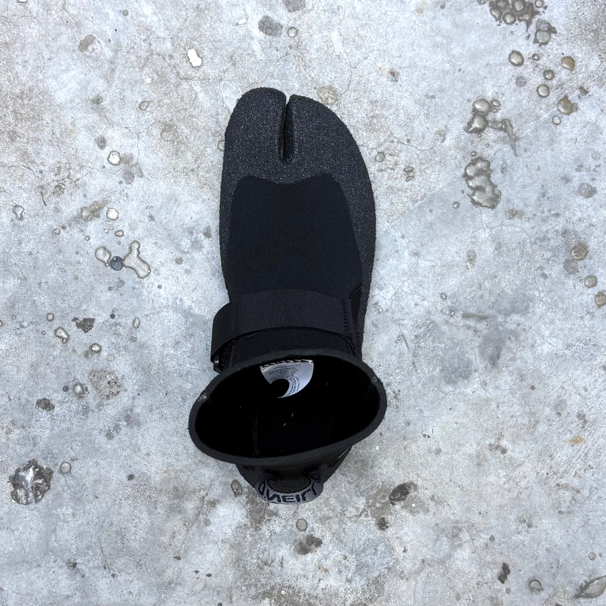 Black split-foot wetsuit on a textured gray surface