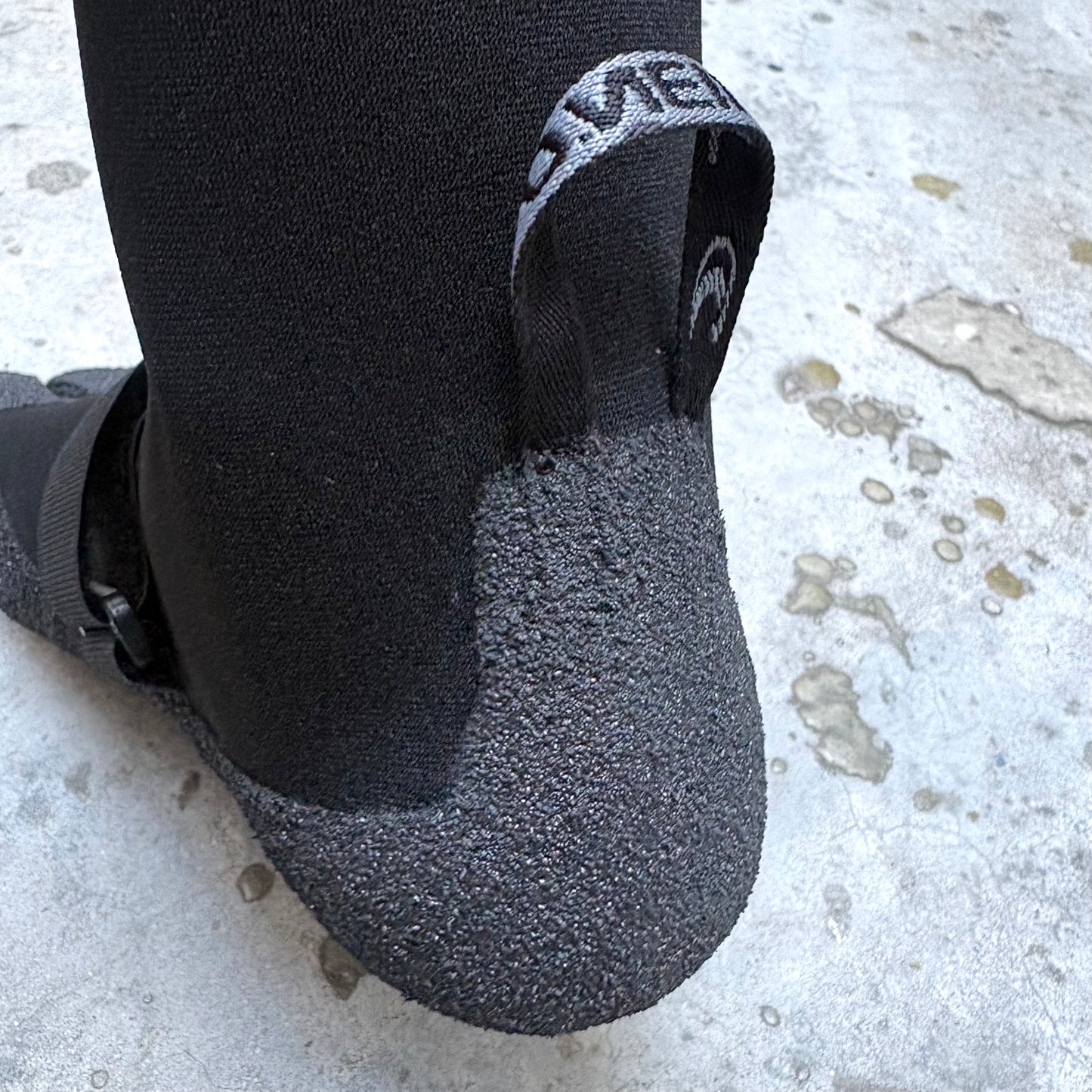 Close-up of a black sock with a brand logo on a textured surface