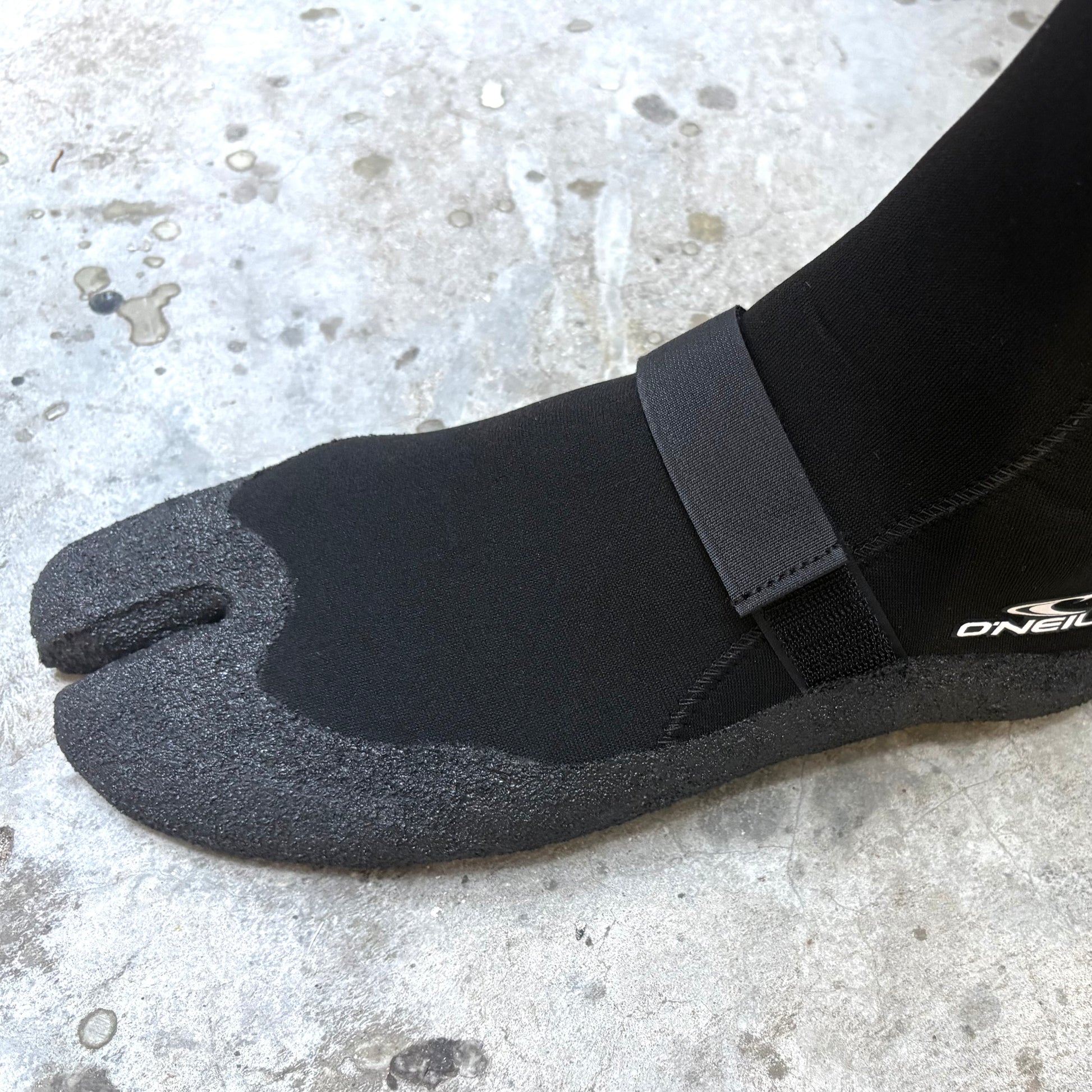 Black tabi sandal with a strap on a concrete surface