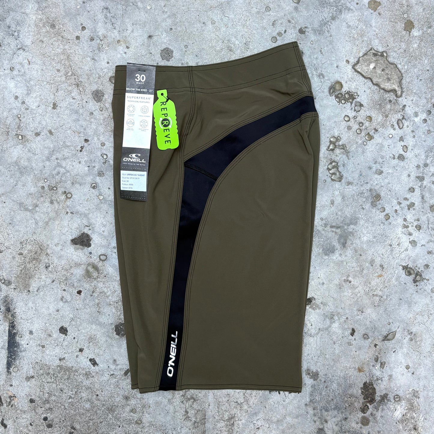 Green athletic shorts with a brand tag on a textured concrete surface