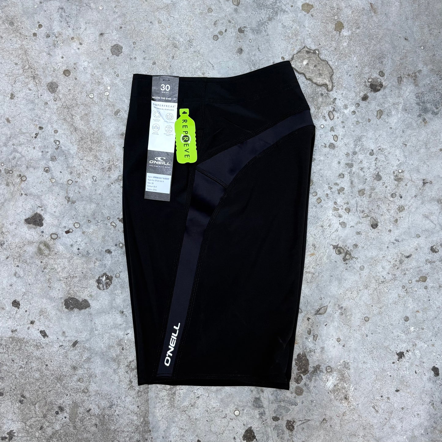 Black athletic shorts with a brand tag on a concrete surface