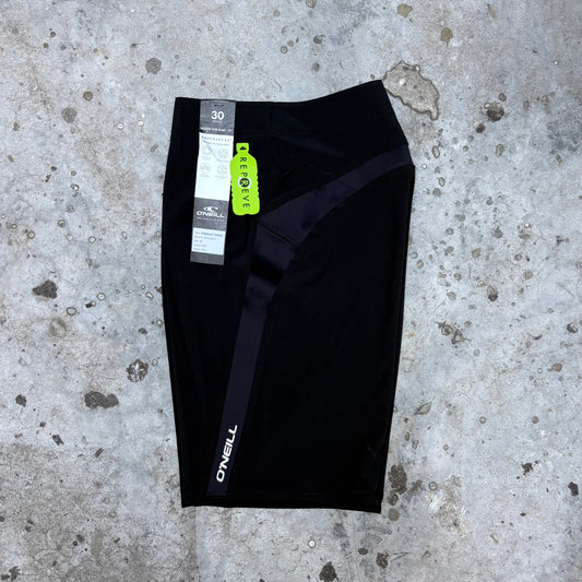 Black athletic shorts with a brand tag on a concrete surface