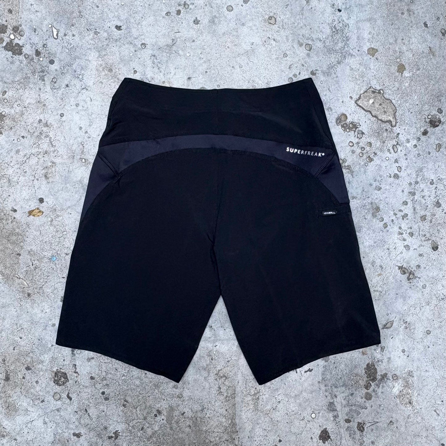 Black shorts with a brand logo on a concrete surface