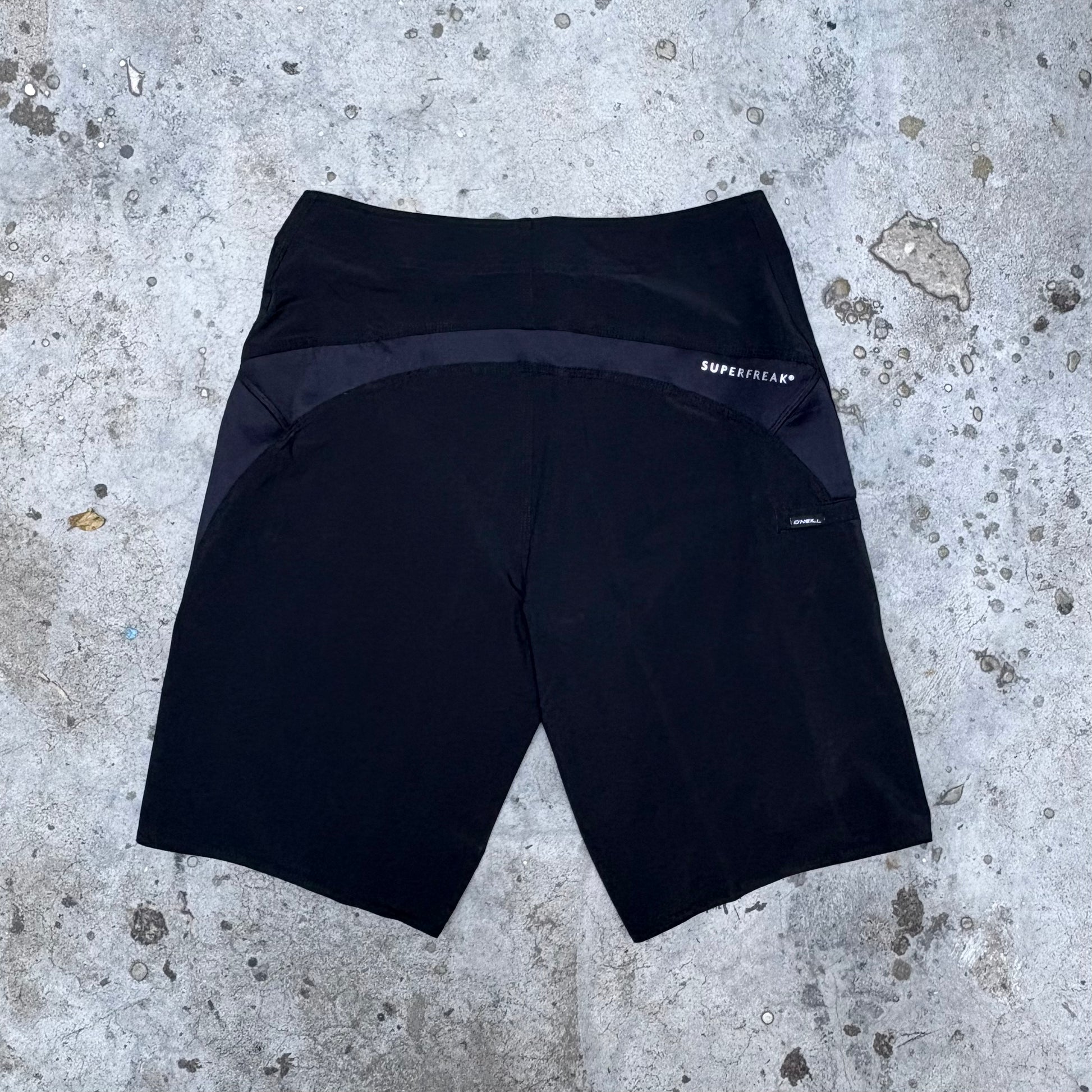 Black shorts with a brand logo on a concrete surface