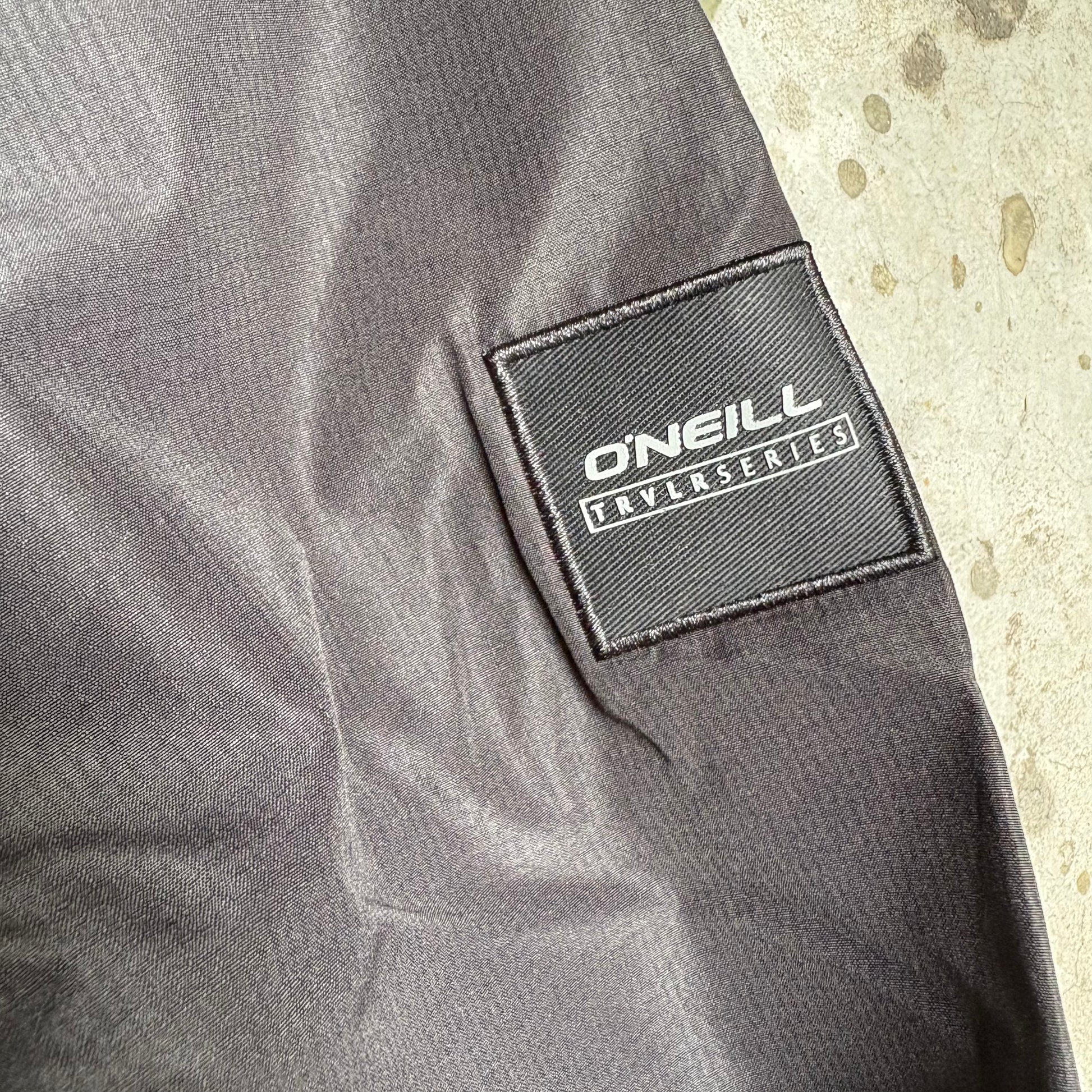 Close-up of a gray jacket with a 'O'Neill' logo on a textured beige background