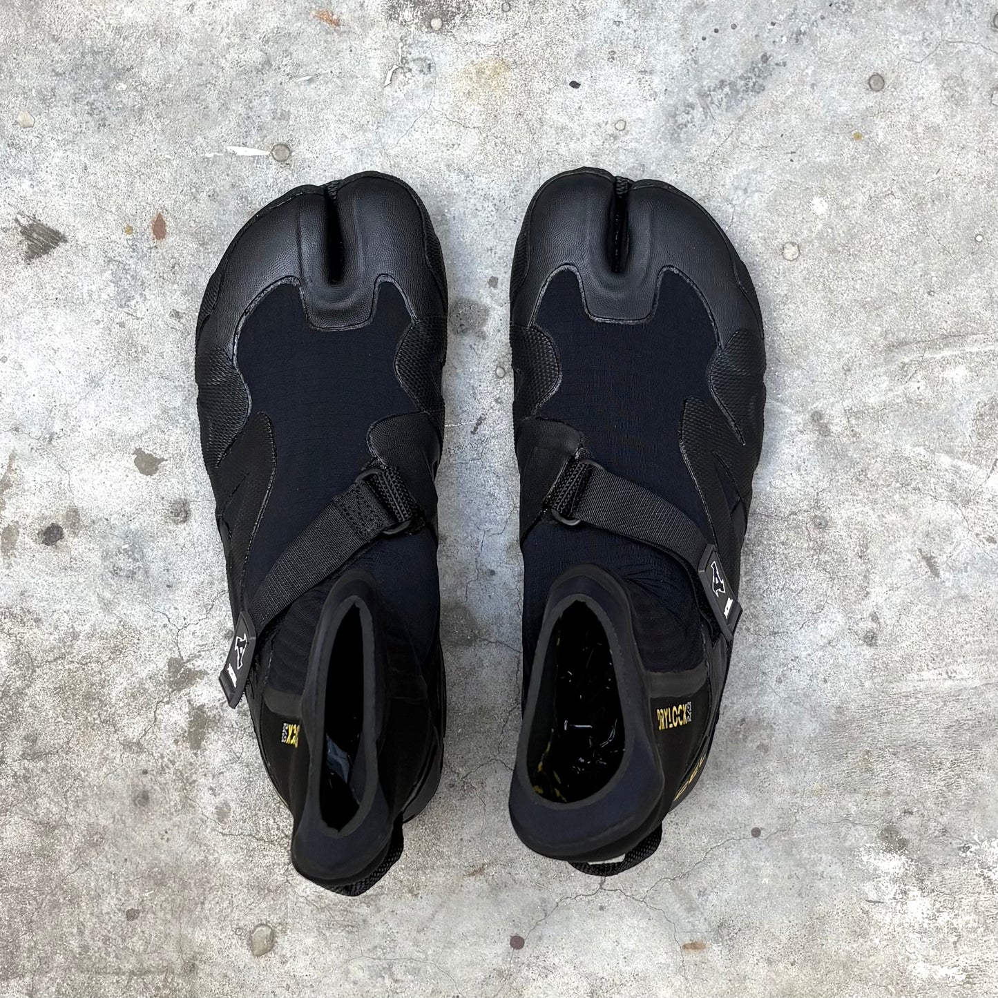 Pair of black surfing boots on a concrete surface