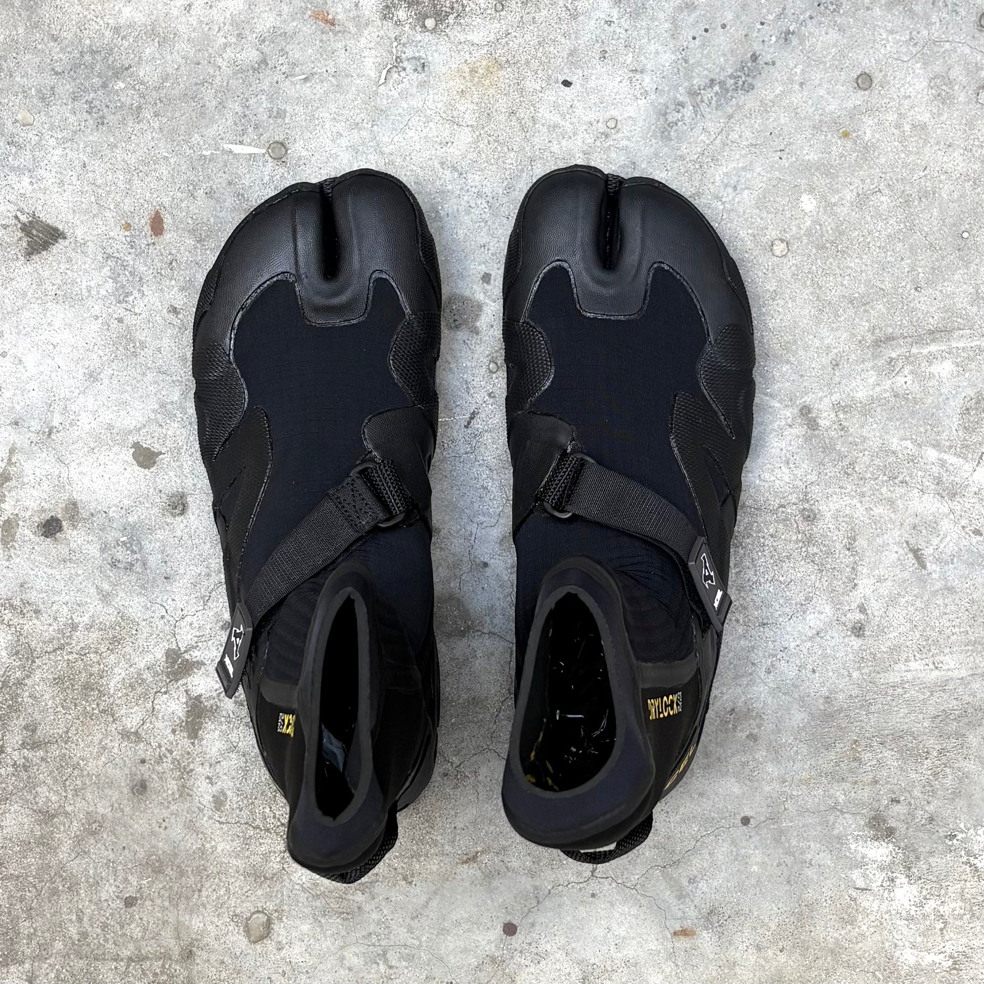Pair of black surfing boots on a concrete surface