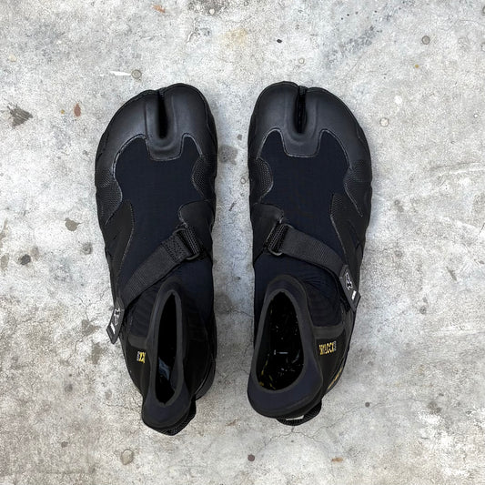 Pair of black surfing boots on a concrete surface