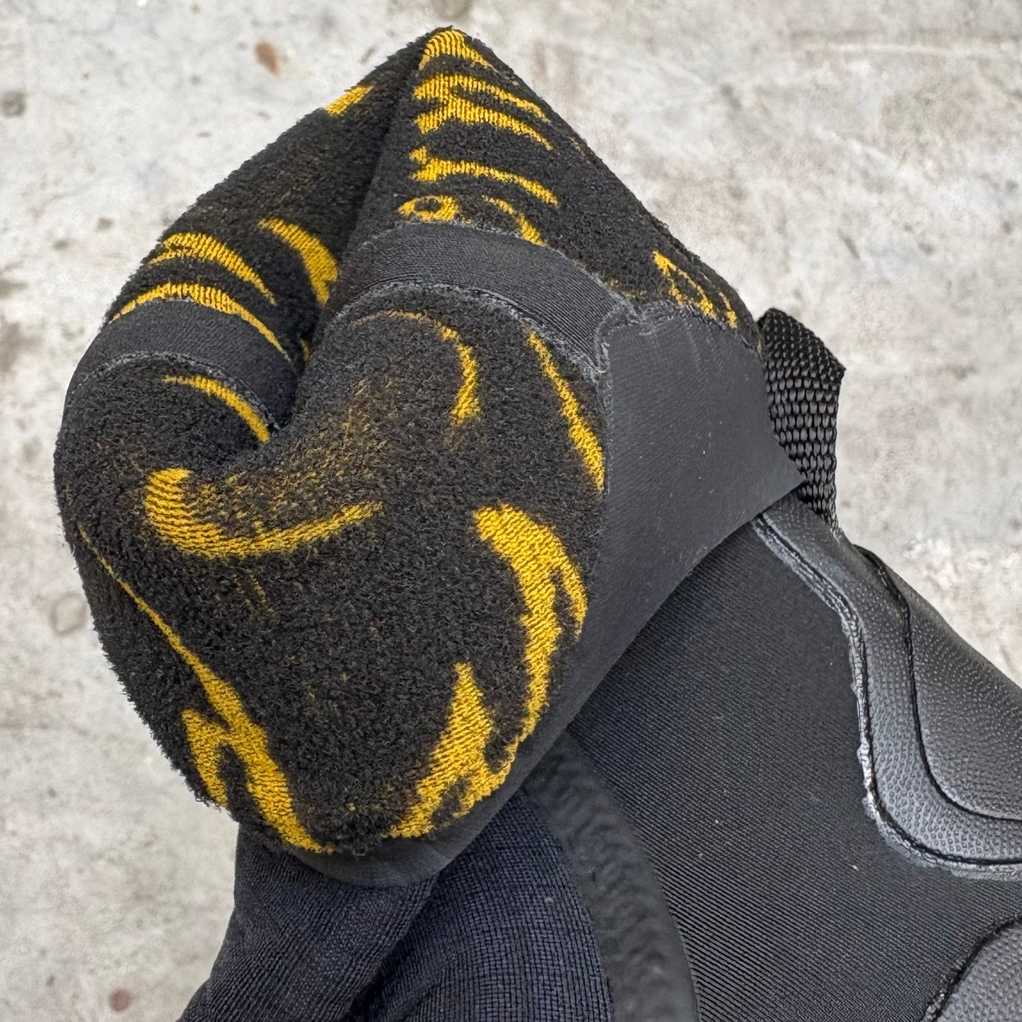 Black surf boot with yellow accents on a textured surface