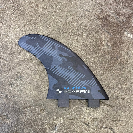 Surfboard fin with Scarfini branding on a concrete surface