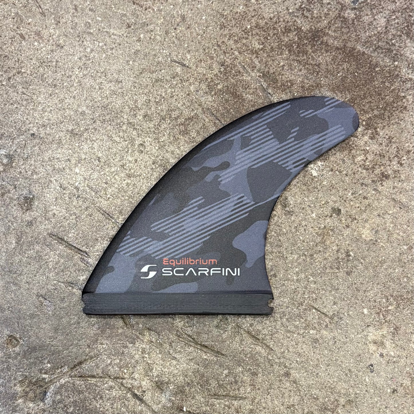 Black and gray fin with 'Equilibrium Scarfini' branding on a concrete surface